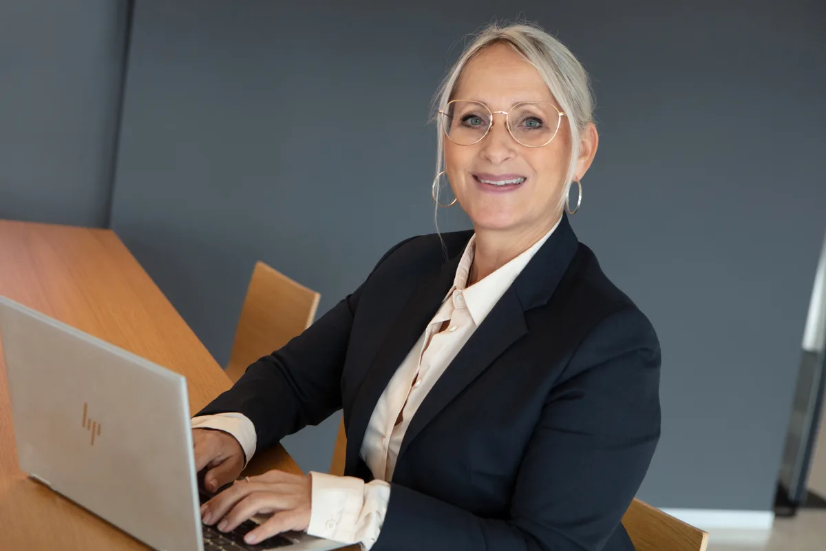 Frau sitzt hinter einem Laptop an einem Tisch.